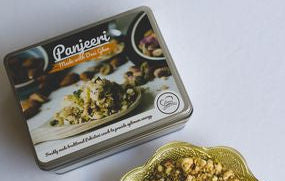Tin of Panjeeri with a decorative lid featuring branding on a white background